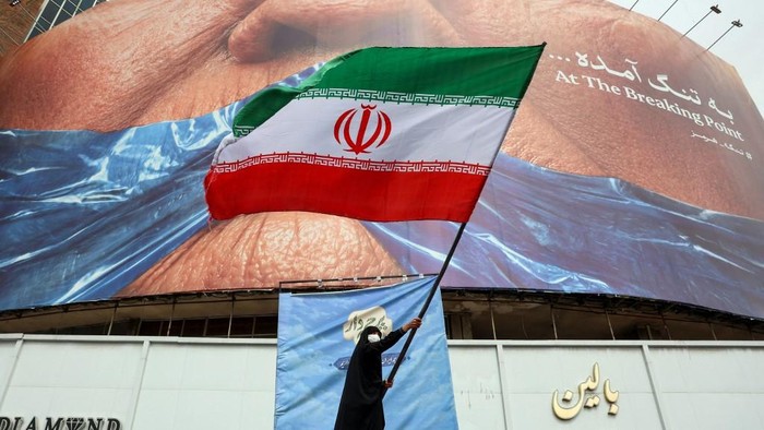 seorang-wanita-melambaikan-bendera-irandi-depan-billboard-anti-as-di-alun-alun-valiasr-teheran-1779178472111_169
